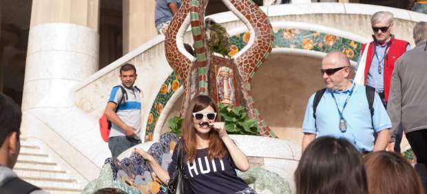 Una turista es fa una foto al popular Drac de Gaudí del Park Güell.