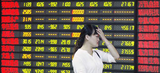 Una inversora pasa delante de una pantalla que muestra información bursátil en una compañía de compraventa de acciones en Huaibei, provincia de Anhui (China) este 24 de agosto de 2015. EFE/Woo He