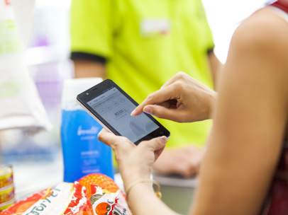 Una persona pagando con su teléfono móvil en un supermercado.