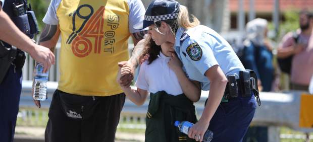 Una oficial de policía abraza a una niña después del accidente de vehículo donde murieron dos menores.