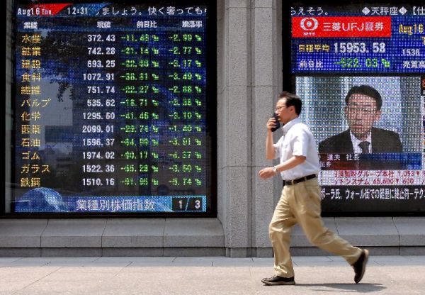 Un hombre pasa por delante de un panel que muestra las cotizaciones del mercado en Tokio. Un hombre pasa por delante de un panel que muestra las cotizaciones del mercado en Tokio.