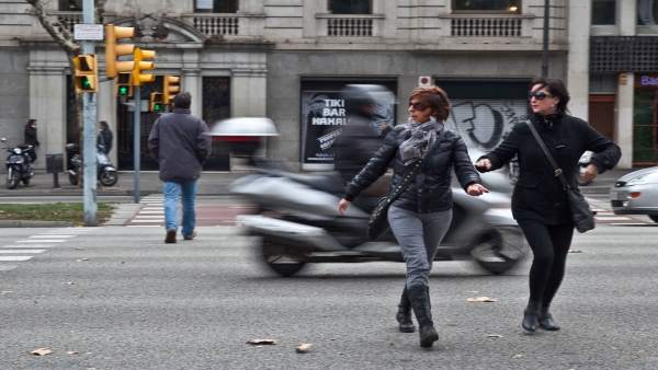 Dos peatones corren tras el paso de una moto en la Diagonal. Dos peatones corren tras el paso de una moto en la Diagonal.