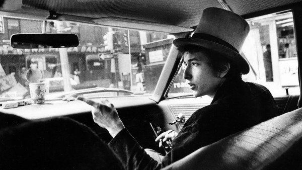 'Bob Dylan with top hat pointing in car' 'Bob Dylan with top hat pointing in car'