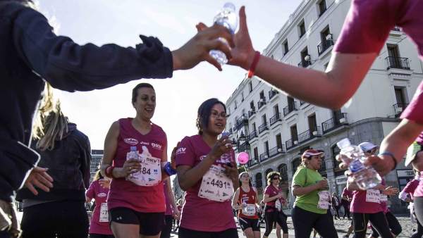 Un voluntario le da una botella de agua a una corredora Un voluntario le da una botella de agua a una corredora