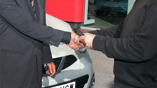 Un hombre adquiere un coche en un concesionario Un hombre adquiere un coche en un concesionario