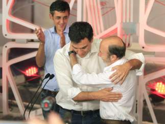 Rubalcaba abraza a Sánchez tras ganar las primarias del PSOE mientras Madina aplaude.