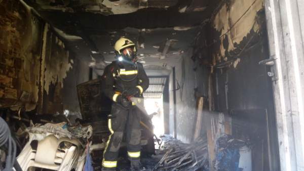 Un bombero inspecciona el garaje incendiado Un bombero inspecciona el garaje incendiado