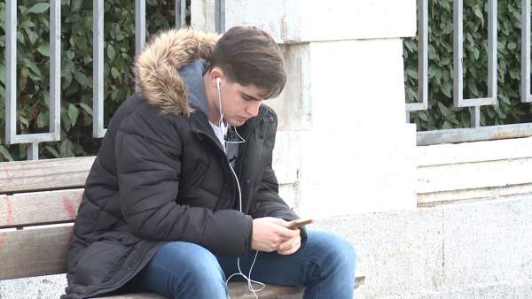 Un joven consulta su teléfono móvil Un joven consulta su teléfono móvil