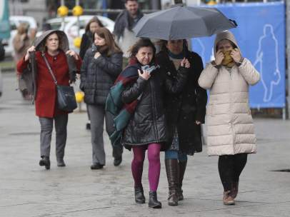 Varias personas se protegen del frío y la nieve en Madrid.