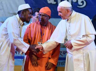 El papa Francisco le da la mano a un refugiado rohingya.