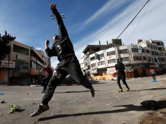 Varios hombres lanzan piedras a las tropas israelíes en Hebrón (Palestina).