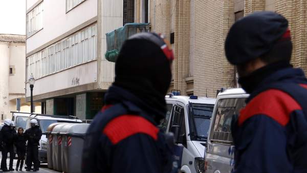 Agentes de la Guàrdia Urbana de Barcelona desalojan a una chica de la Residència d'Estudiants Autogestionada del Raval. En primer plano, dos mossos custodian la entrada a la calle. Agentes de la Guàrdia Urbana de Barcelona desalojan a una chica de la Residència d'Estudiants Autogestionada del Raval. En primer plano, dos mossos custodian la entrada a la calle.
