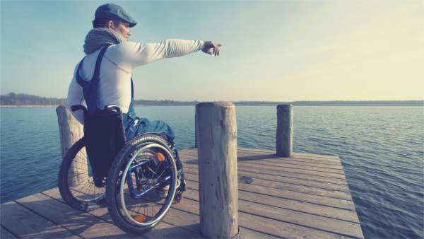 Un joven en silla de ruedas señala el horizonte Un joven en silla de ruedas señala el horizonte