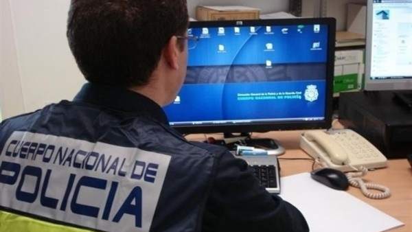 Un agente de Policía frente a un ordenador Un agente de Policía frente a un ordenador