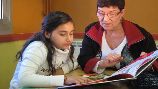 Voluntaria Ayuda A Leer A Una Niña Voluntaria Ayuda A Leer A Una Niña