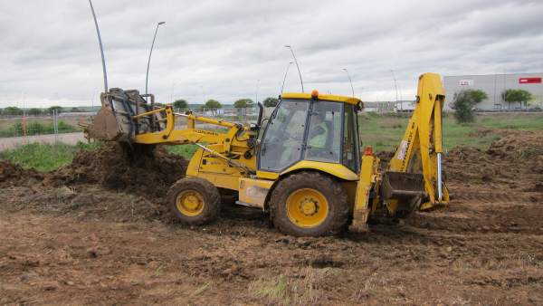 Un trabajador con una excavadora en una obra Un trabajador con una excavadora en una obra