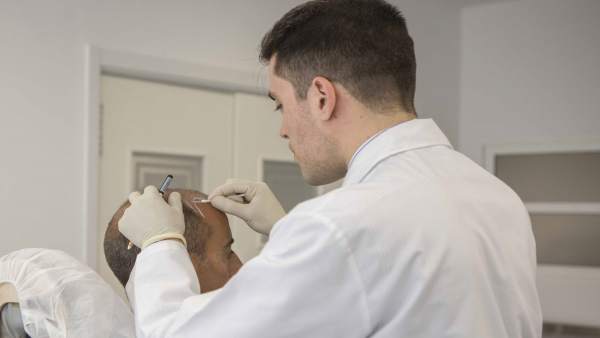 Médico trabajando en un transplante de pelo Médico trabajando en un transplante de pelo