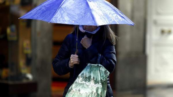 Una mujer sostiene un paraguas bajo la lluvia Una mujer sostiene un paraguas bajo la lluvia