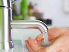 Unas manos sostienen el agua que sale del grifo