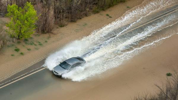 Un coche circula por la recta de Arguedas anegada de agua Un coche circula por la recta de Arguedas anegada de agua