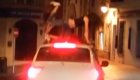 Dos jóvenes bailan sobre el techo de un coche en marcha