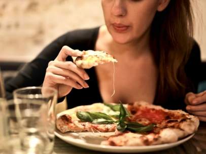 Una mujer, comienzo una porción de pizza