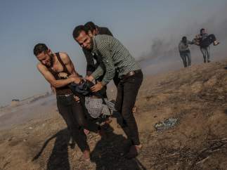 Manifestante palestinos cargan a una mujer herida en la frontera con Israel