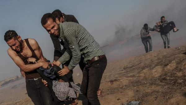 Manifestante palestinos cargan a una mujer herida en la frontera con Israel Manifestante palestinos cargan a una mujer herida en la frontera con Israel
