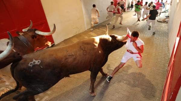 Corredor enganchado por el pañuelo en el encierro de Sanfermines. Corredor enganchado por el pañuelo en el encierro de Sanfermines.