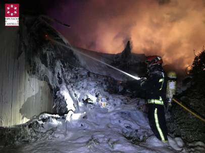 Un operario de los Bomberos sofoca el incendio del camión siniestrado.