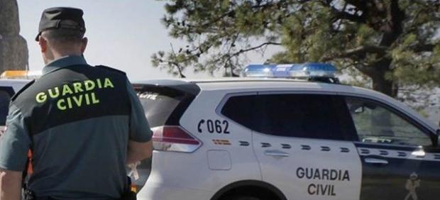 Agente de la Guardia Civil junto a un coche patrulla