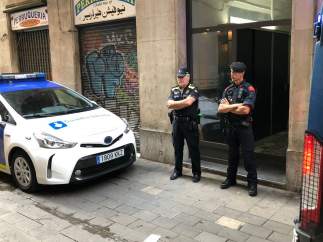 Dos agentes de la Guardia Urbana de Barcelona custodian un piso del Raval