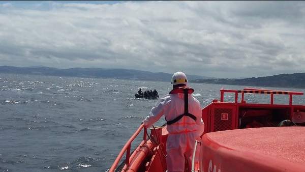 Un operario de Salvamento Marítimo y una patera al fondo Un operario de Salvamento Marítimo y una patera al fondo