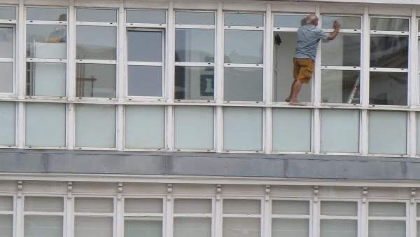 Hombre que limpia los cristales asomado a la ventana en Santander Hombre que limpia los cristales asomado a la ventana en Santander
