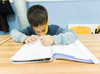 Un niño escribe en un libro de texto