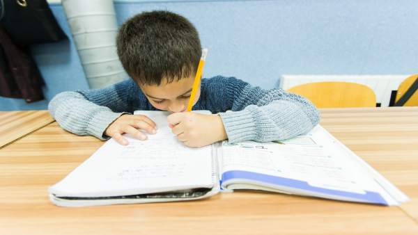 Un niño escribe en un libro de texto Un niño escribe en un libro de texto