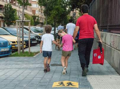 Un padre con sus hijos rumbo al colegio.