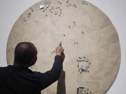 Francis Kéré junto a una maqueta que representa la aldea de Gando
