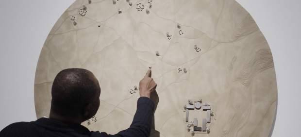 Francis Kéré junto a una maqueta que representa la aldea de Gando