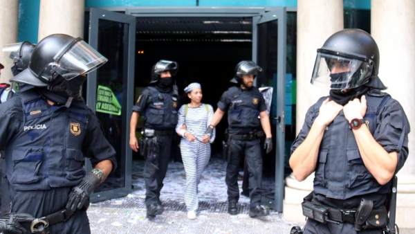 Agentes de los Mossos d'Esquadra desalojan a una activista de la PAH de la sede de Bankia en la calle Casp de Barcelona. Agentes de los Mossos d'Esquadra desalojan a una activista de la PAH de la sede de Bankia en la calle Casp de Barcelona.