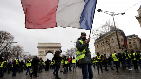 Un hombre con chaleco amarillo porta bandera francesa en una manifestación Un hombre con chaleco amarillo porta bandera francesa en una manifestación