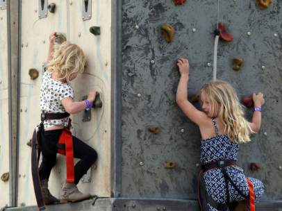 Dos niñas escalan en un rocódromo