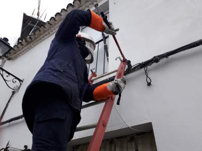 Un operador de suministro eléctrico corta una acometida ilegal.