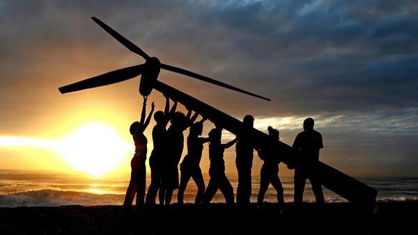 Greenpeace and Tcktcktck volunteers raise a wind turbine on the beach at dawn in Greenpeace and Tcktcktck volunteers raise a wind turbine on the beach at dawn in