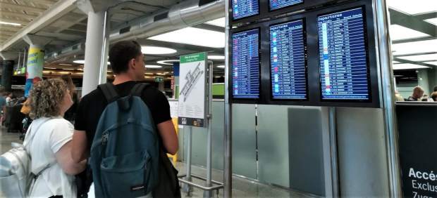 Dos viajeros consultan la información de vuelos en las pantallas del aeropuerto