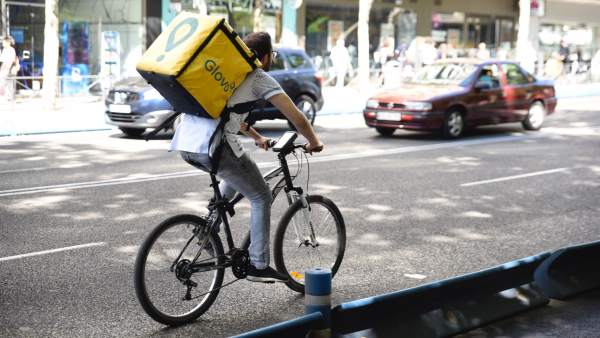 Trabajador de la empresa Glovo montando en bicicleta Trabajador de la empresa Glovo montando en bicicleta