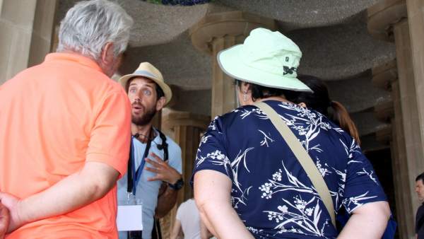 Dos turistas siguen las explicaciones de un guía turístico en el Park Güell. Dos turistas siguen las explicaciones de un guía turístico en el Park Güell.