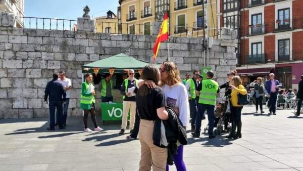 Una pareja lesbiana besándose frente a un puesto de Vox Una pareja lesbiana besándose frente a un puesto de Vox