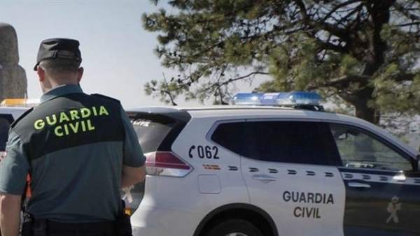 Agente de la Guardia Civil junto a un coche patrulla Agente de la Guardia Civil junto a un coche patrulla