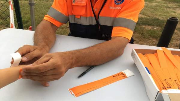 Un agente de Protección Civil coloca un brazalete a un niño. Un agente de Protección Civil coloca un brazalete a un niño.
